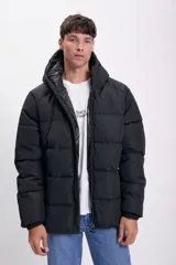Campera puffer negra con diseño capitoneado, cierre frontal completo y capucha integrada.