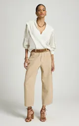 Sweater calado de punto color blanco, de corte recto con amplio cuello tipo polo y escote en V. Presenta mangas largas con volumen, puños ajustados y detalles de volados texturizados en la parte delantera y en las mangas.