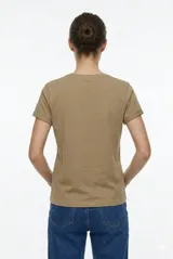 Remera de manga corta color beige, con cuello redondo y diseño al cuerpo. Presenta un estampado frontal multicolor de estilo veraniego con temática marina y detalles con glitter.