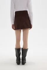 Falda mini de corte recto confeccionada en gamuza sintética color marrón, con cierre frontal de botón y presillas para cinturón.