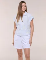 Camisa celeste con bordado floral en color crudo, de corte semi holgado, cuello camisero, manga corta japonesa con dobladillo y cierre frontal de botones.