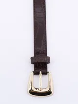 Cinturón negro con hebilla dorada de forma cuadrada y textura símil cuero de cocodrilo.