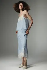 Top de estilo lencero color celeste, con escote recto y tirantes finos decorados con puntilla de encaje blanco. Presenta un detalle de encaje floral en el pecho.