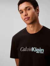 Remera de algodón con cuello redondo y manga corta, presenta un estampado frontal con el logo de la marca en estilo cursivo.