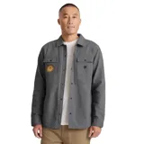 Campera gris de algodón canvas, estilo camisa, con bordado de un sol en el bolsillo del pecho. Tiene dos bolsillos con solapa en el pecho y cierre con botones. Corte recto y holgado.