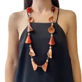 Collar largo con cordón, cuentas doradas y dijes de resina color naranja con forma de calas.