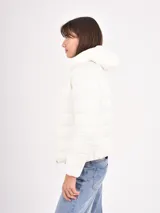 Campera puffer blanca con cuello alto, cierre frontal y diseño acolchado horizontal.