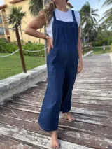 Mono largo de denim azul, corte oversize, con tirantes regulables y bolsillos laterales.