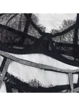 Conjunto de lencería de encaje negro con tirantes de strass brillante, compuesto por soutiene con detalles de encaje en los bordes, bombacha estilo colaless y portaligas con tiras ajustables decoradas con pedrería.