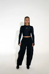 Pantalón sastrero de corte recto y tiro alto, confeccionado en lycra de color negro. Presenta cierre frontal con botón, bolsillos laterales y un diseño que combina la estructura de la sastrería con la comodidad de un tejido elástico.