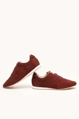Zapatilla de gamuza color bordó con cordones bicolores, interior de cuero vacuno y suela de caucho blanca y beige.