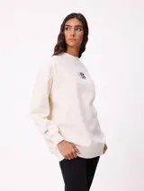 Sweater negro de corte holgado con estampado trasero de flores y el logo "Rusty" en colores neón.