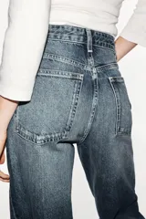 Jeans de tiro alto y estilo wide leg, con diseño de cinco bolsillos, lavado oscuro con efecto desgastado, pierna ancha larga y bajo sin costuras.