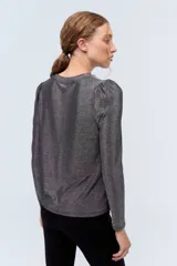 Remera plateada de lurex con escote redondo, calce al cuerpo y mangas largas estilo princesa.