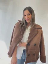 Chaqueta negra con forro tipo corderito, doble botonadura y cuello solapa.