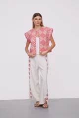 Chaleco corto con estampado geométrico en tonos rosa y rojo, sin mangas y cuello redondo.