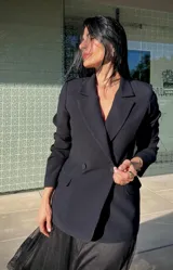 Blazer negro de corte sastre, con solapas clásicas, cierre frontal de doble botonadura y bolsillos laterales con solapa.