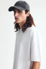 Remera blanca de manga corta, cuello redondo ribeteado y corte relajado con hombros caídos. Fabricada en punto liviano con fibra COOLMAX.