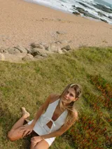 Top blanco de gabardina con tiras ajustables en cuello y delantero, y recortes irregulares.