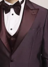 Traje formal de tres piezas en tono tostado brillante, compuesto por saco con solapas en contraste, pantalón de corte recto y chaleco a juego, acompañado de moño.