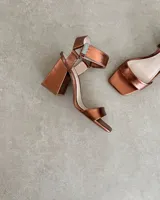 Sandalia de taco cuadrado alto, con diseño de punta cuadrada, tira delantera ancha y tira ajustable en el tobillo con hebilla metálica.