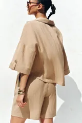 Bermuda de tiro alto color azul marino, con pinzas delanteras, bolsillos laterales y cinturón trenzado color marrón.