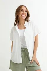 Camisa blanca de lino con cuello clásico, manga corta y cierre frontal con botones.