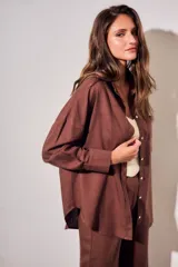 Camisa oversize color marrón, confeccionada en mezcla de viscosa y lino, con cuello clásico, cierre frontal con botones y un bolsillo aplicado en el pecho.