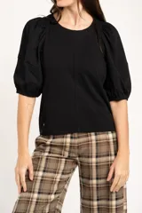Remera de algodón negro con mangas cortas abullonadas, cuello redondo y costura central frontal.