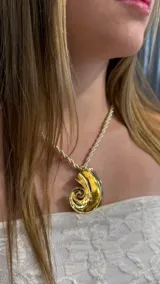 Choker con cordón trenzado color crema y dije grande en forma de espiral con acabado dorado texturizado.