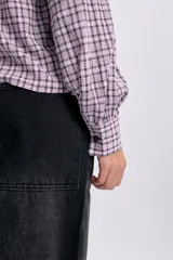 Camisa de manga larga con estampado a cuadros en tonos violeta y blanco, con cuello bobo grande con volados y cierre frontal de botones.