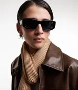 Bufanda beige de punto grueso con efecto melange y flecos en los bordes.