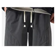 Pantalón cargo ancho de algodón gabardina color beige claro, con cintura elástica y regulable, y múltiples bolsillos cargo con pliegues en las piernas.