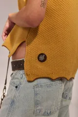 Chaleco de punto de lambswool color mostaza, sin mangas, con cuello redondo y diseño de ochos en la parte delantera.