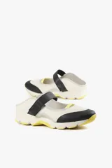 Zapato de diseño urbano color blanco con detalles en negro y amarillo, suela dentada y tira de velcro en el empeine.