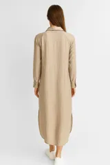 Vestido camisero blanco de lino, corte holgado, largo midi, con cuello camisero, abotonadura frontal y mangas 3/4 con puños. Incluye un bolsillo de parche en el pecho y aberturas laterales en el ruedo.