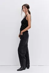 Blusa de punto sin mangas, color negro, con escote redondo y detalle de pequeñas tachas metálicas plateadas distribuidas por toda la prenda.