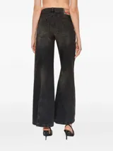 Jeans Diesel modelo D-Akii de corte flare y tiro alto, en denim color negro con efecto desgastado. Presenta bolsillos delanteros grandes, costuras decorativas verticales y perneras anchas.