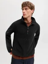 Campera de polar negra con cuello alto y cierre frontal parcial. Presenta el logo de la marca bordado en el pecho y puños con abertura para el pulgar.