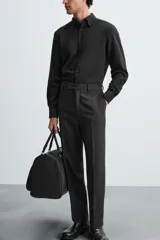 Camisa negra de corte slim fit, con cuello italiano y manga larga con puño abotonado. Cierre frontal de botonadura.