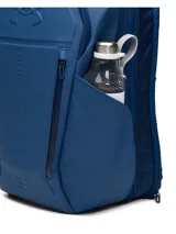 Mochila Under Armour de color azul marino, diseñada con tirantes acolchados y texturizados para mayor comodidad, correa ajustable en el pecho con hebilla y el logo de la marca en relieve.