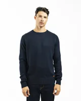 Buzo tejido de punto con cuello redondo, manga larga y puños y ruedo acanalados. Presenta un diseño clásico y versátil con un pequeño detalle de etiqueta en el lateral inferior.