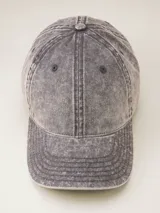 Gorra de béisbol color gris oscuro con efecto lavado o acid wash, visera curva y panel frontal estructurado. Presenta una pequeña etiqueta negra cosida en el lateral trasero.