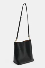 Bolso de hombro formato saca de color negro, con cierre mediante clip metálico y un compartimento interior extraíble con cremallera. Incluye un asa de hombro con diseño estampado y detalles metálicos dorados.