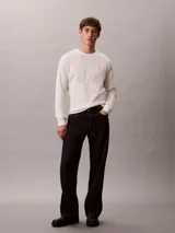 Remera de manga larga Calvin Klein de color blanco off-white, confeccionada en tejido de punto térmico con textura de nido de abeja. Presenta cuello redondo, puños acanalados y un pequeño logo bordado en el pecho.