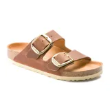 Sandalia Birkenstock modelo Arizona con dos correas anchas de cuero engrasado color cognac y hebillas grandes metálicas doradas. Presenta plantilla anatómica de corcho y suela de goma.