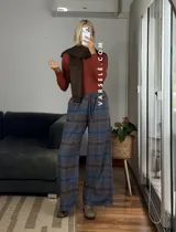 Pantalón tipo palazo de corte amplio y tiro alto, confeccionado en tela con estampado de cuadros escoceses en tonos marrones, blancos y negros. Cuenta con cintura elástica y bolsillos laterales.