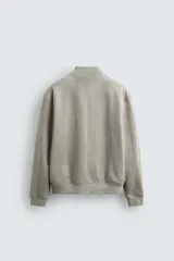 Cazadora bomber negra de corte regular fit, confeccionada en tejido efecto ante. Cuenta con cuello, puños y bajo en rib elástico, manga larga, bolsillos de vivo en la cadera y un bolsillo interior. Cierre frontal con cremallera.