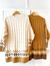 Maxi buzo tejido de punto con diseño de trenzas verticales, cuello redondo y puños acanalados. Presenta un estampado geométrico estilo nórdico en el ruedo y en los puños.