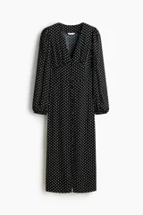 Vestido midi negro con estampado de lunares blancos, escote en V pronunciado, botones forrados frontales y mangas largas abullonadas con puños elásticos.
